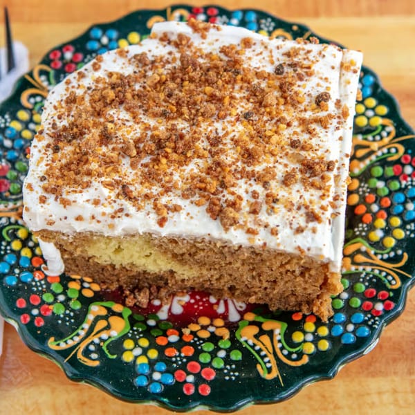 A slice of Sila's Mediterranean Restaurant's cake with white frosting and crumbled topping on a colorful plate.