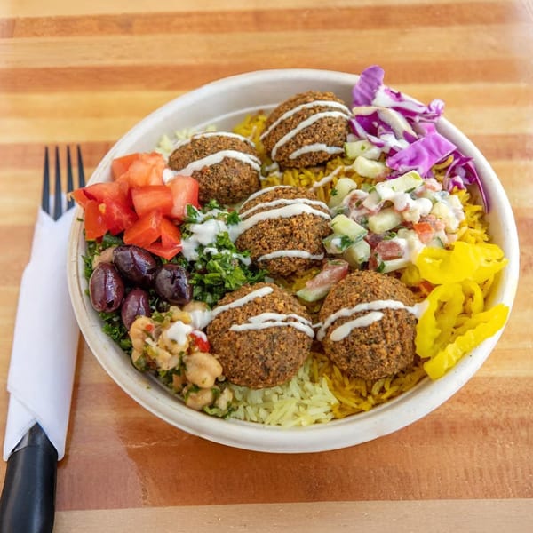 A Sila's Mediterranean falafel bowl with rice, tomatoes, olives, chickpeas, and pickled peppers.