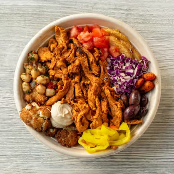 Sila's Mediterranean Restaurant bowl with chicken shawarma, hummus, chickpeas, tomatoes, cabbage, olives, and peppers.