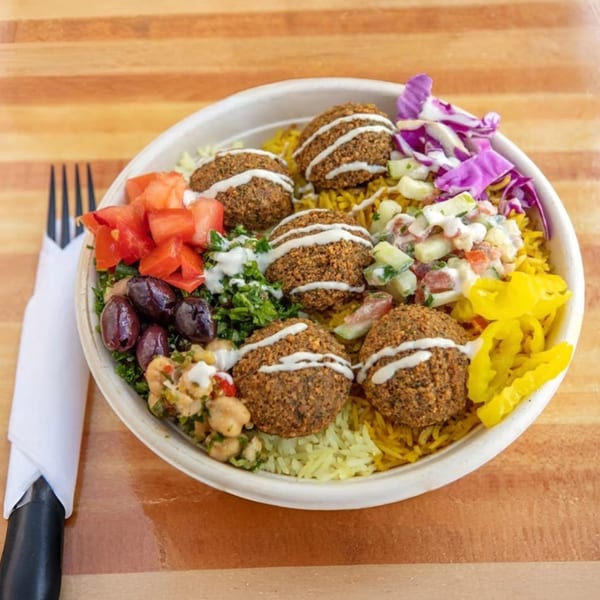 A Sila's Mediterranean falafel bowl with rice, tomatoes, olives, and pickled peppers.